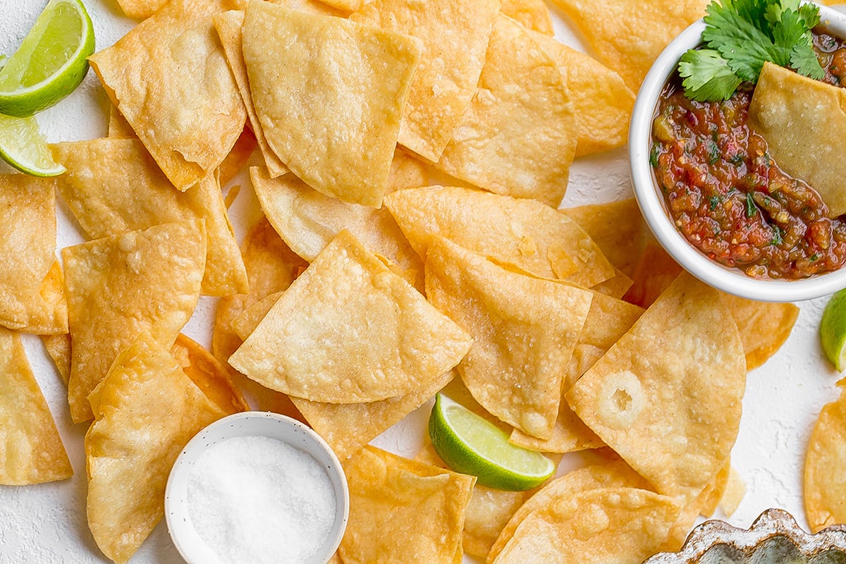 overhead shot of tortillas chips with salt, lime and salsa