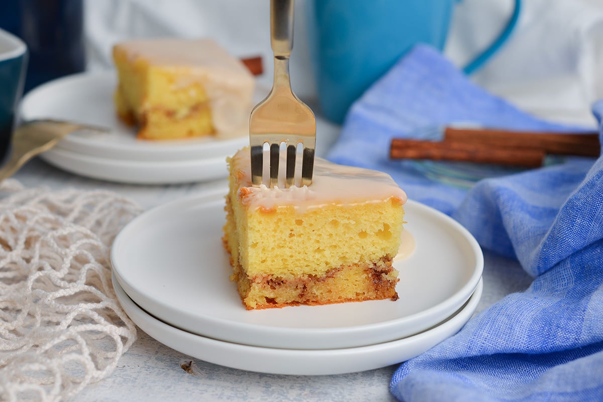 straight on shot of fork digging into slice of honey bun cake on plate