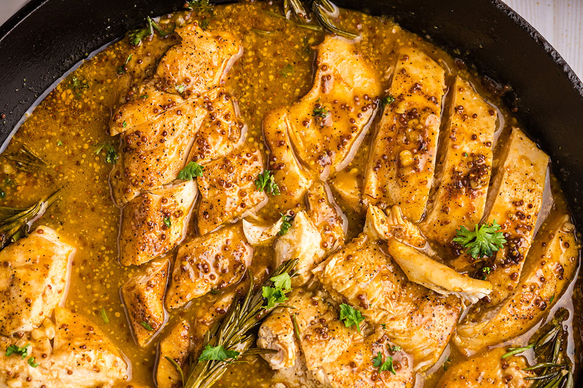 close up overhead shot of sliced honey mustard chicken in pan