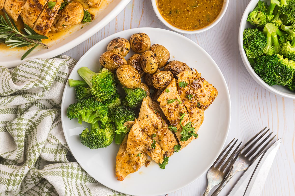 overhead shot of sliced honey mustard chicken on plate with broccoli and potatoes