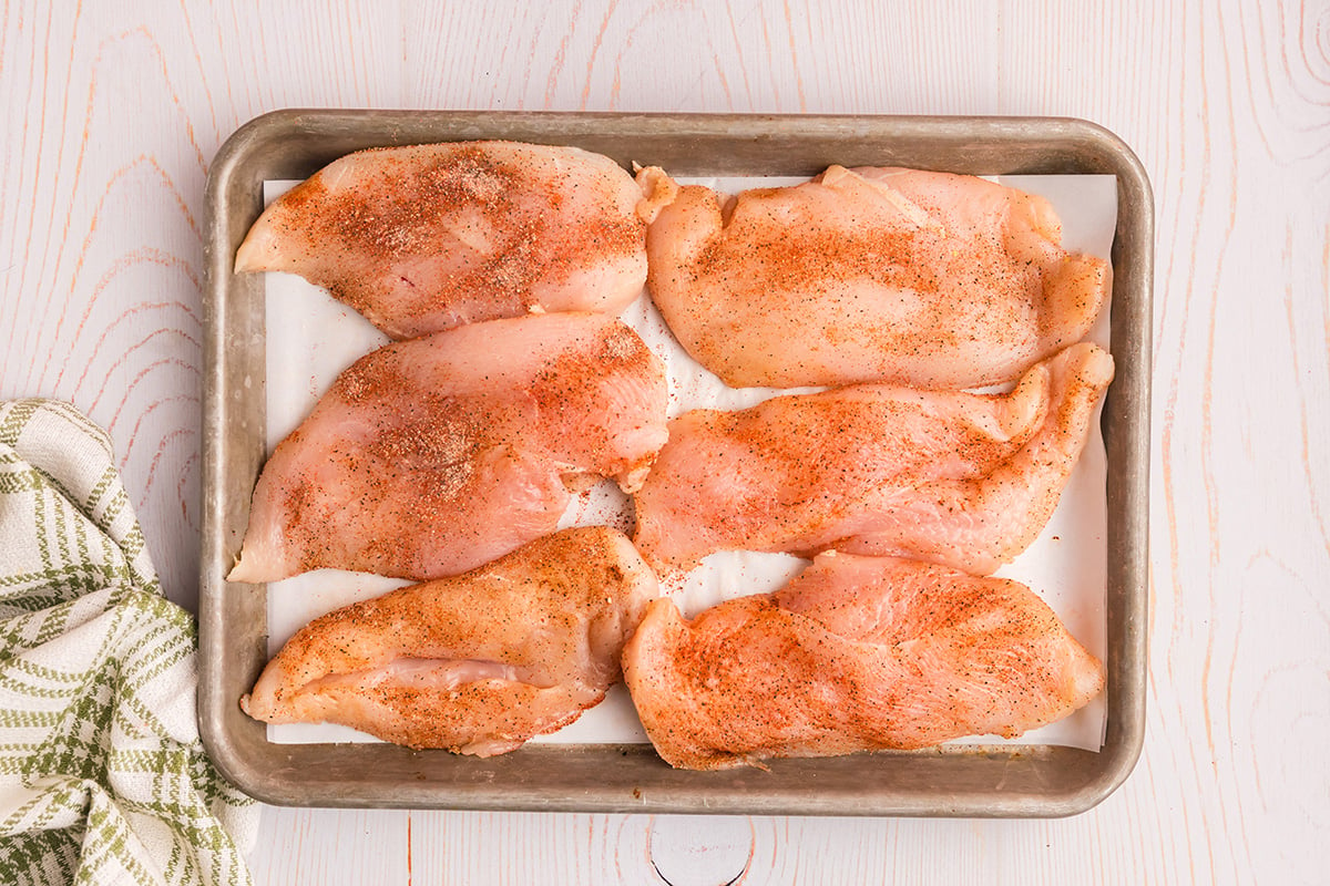 overhead shot of seasoned raw chicken breasts on sheet pan