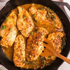 overhead shot of wooden spoon in skillet of honey mustard chicken