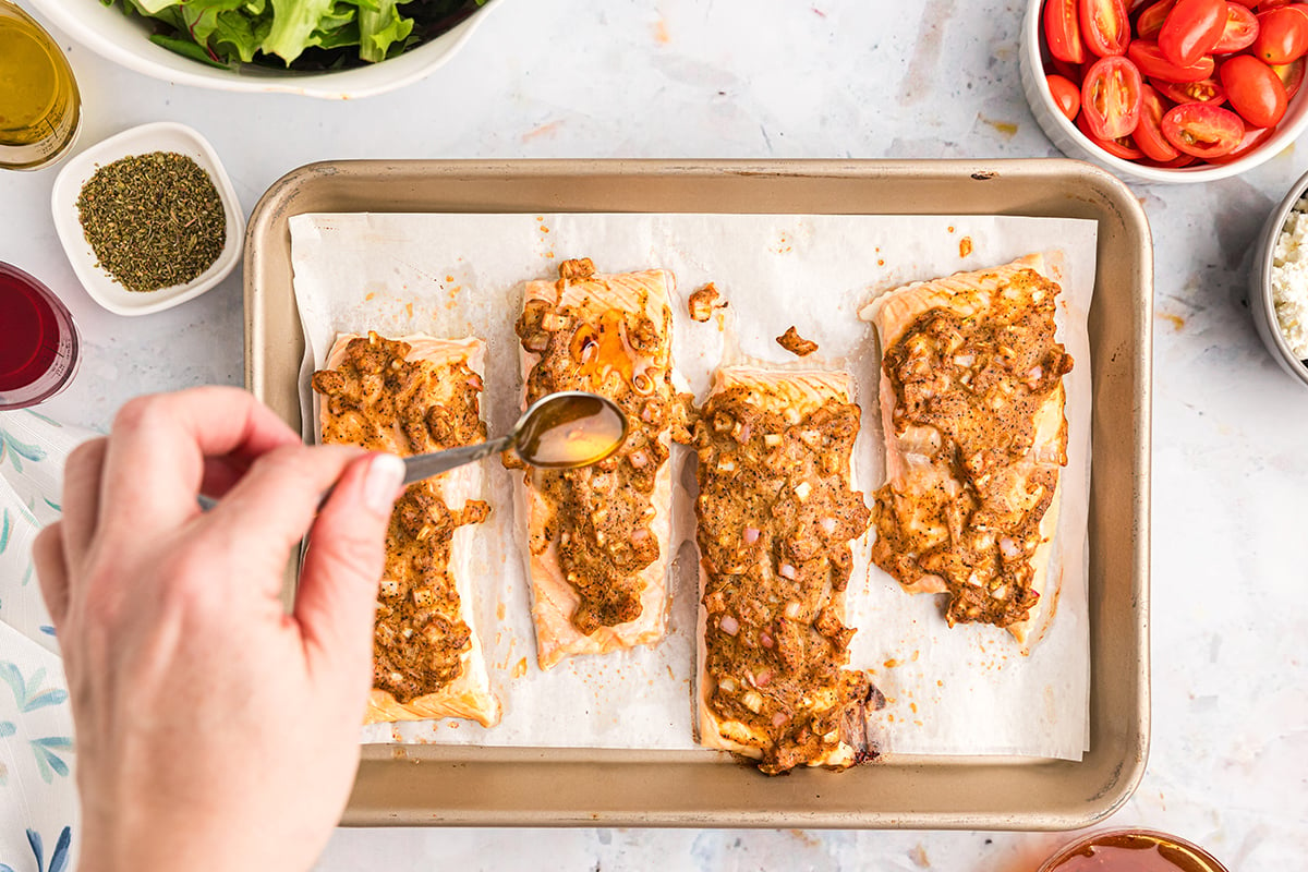 honey drizzling over salmon on sheet pan