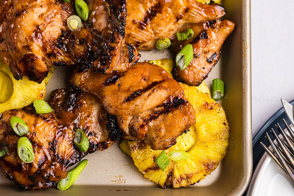 overhead shot of huli huli chicken and pineapple on sheet pan