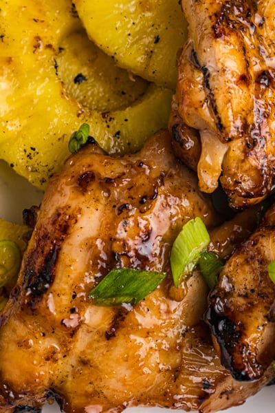 close up overhead shot of huli huli chicken and pineapple on plate