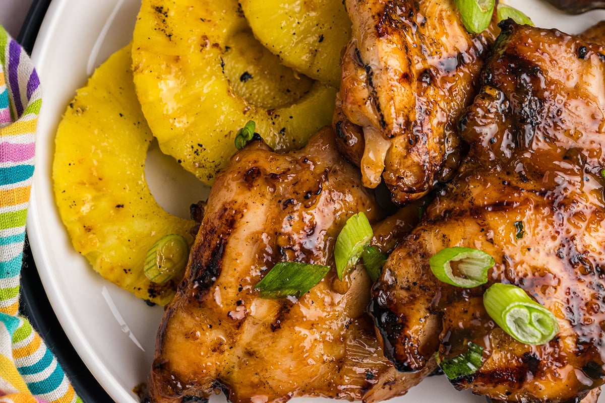 close up overhead shot of huli huli chicken and pineapple on plate