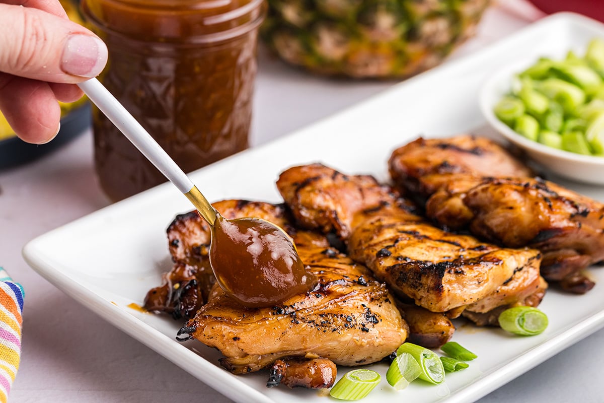 angled shot of spoon adding sauce to chicken