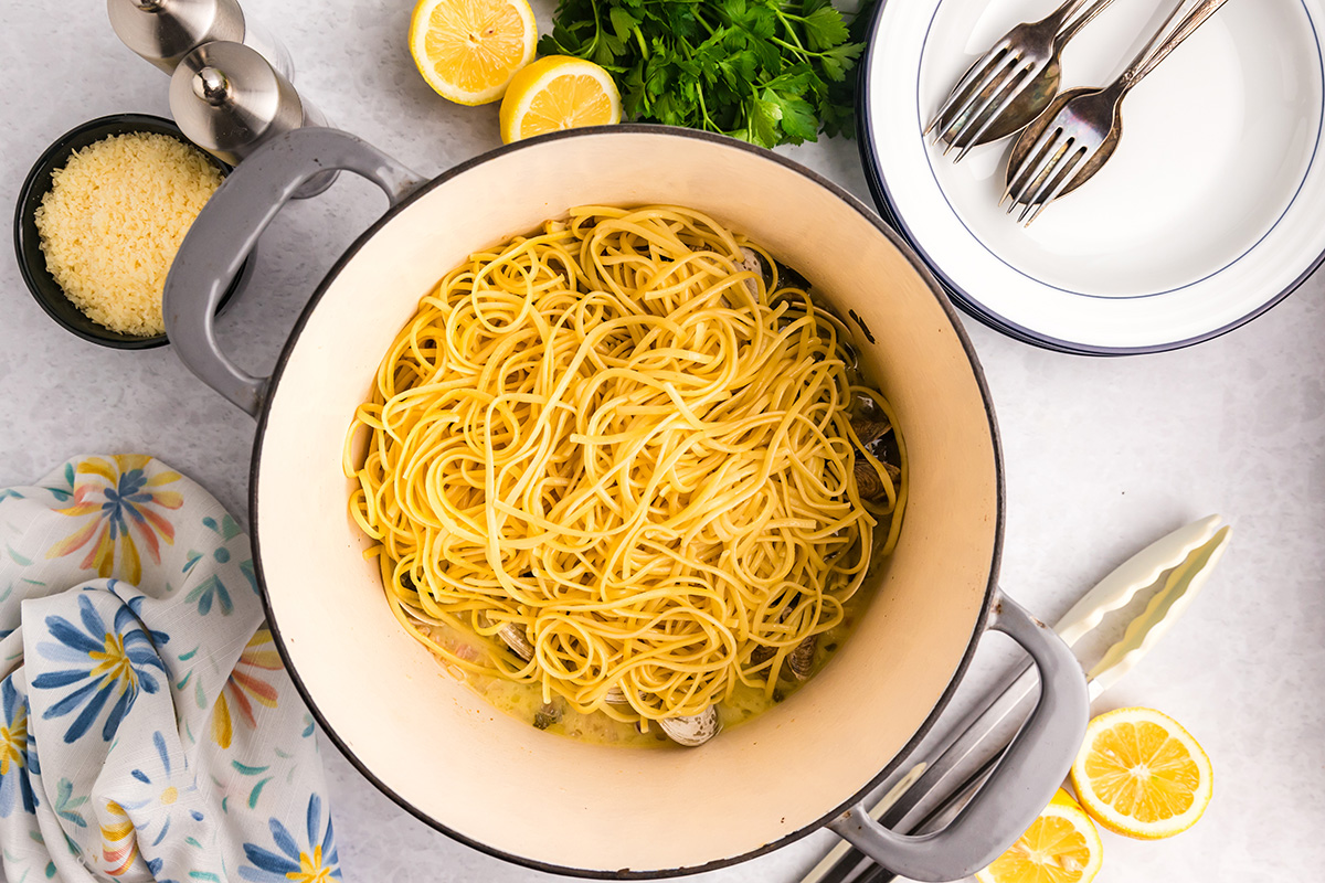 overhead shot of pasta added to white wine clam sauce