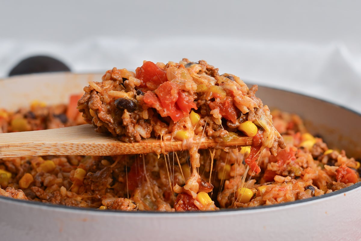 straight on shot of wooden spoon in pan of mexican ground beef casserole