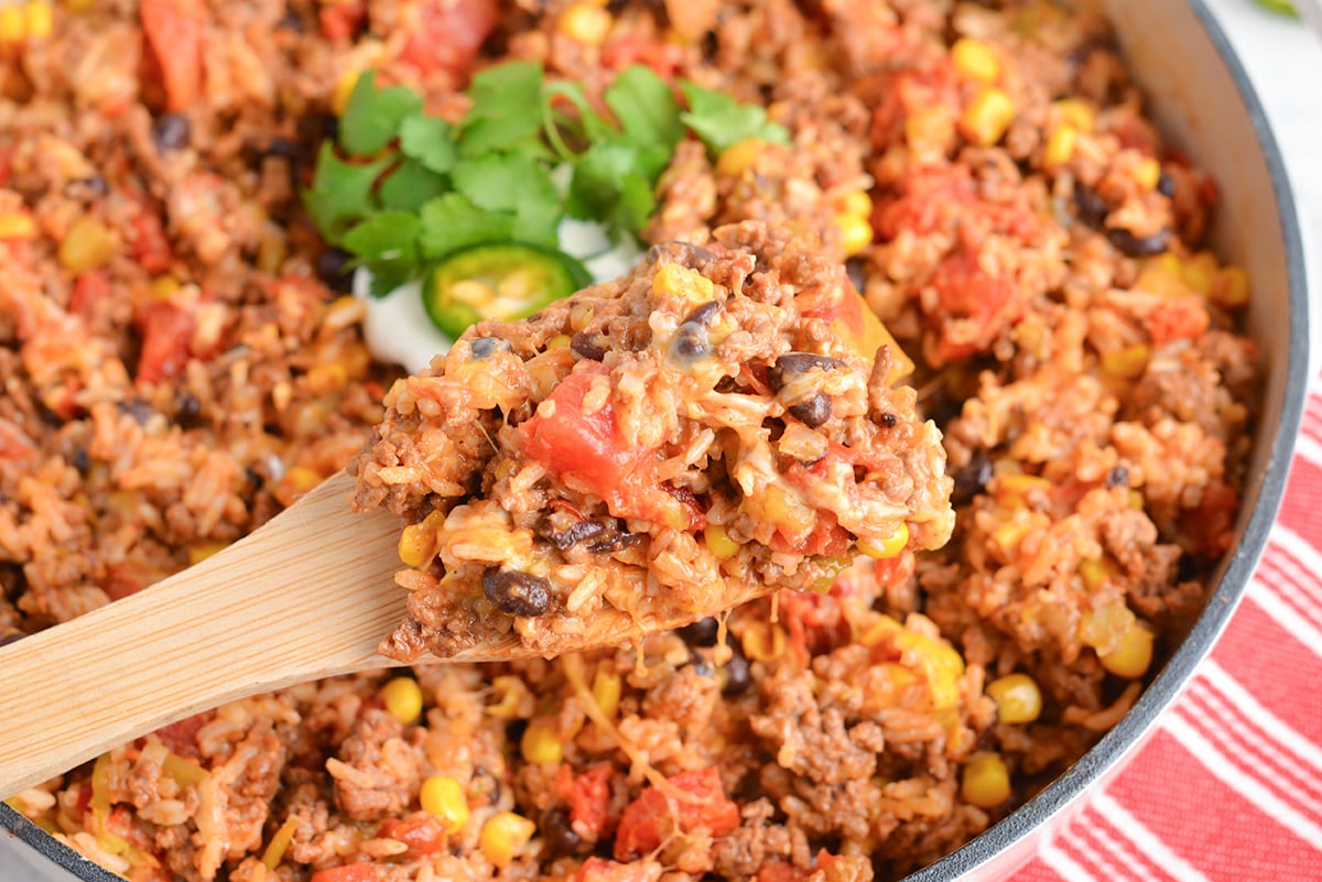 overhead shot of wooden spoon in pan of mexican ground beef casserole