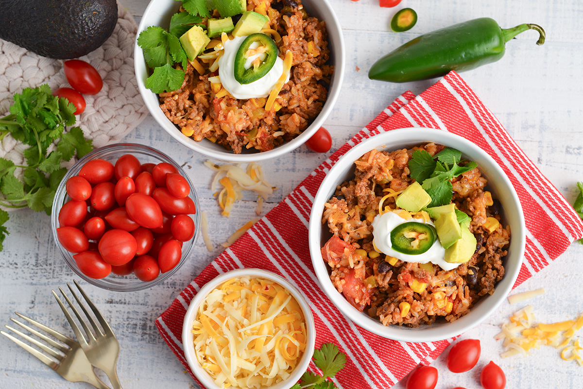 overhead shot of two bowls of mexican ground beef casserole with toppings