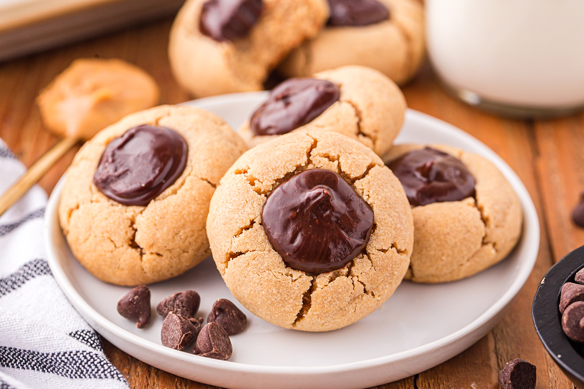 angled shot of four peanut butter thumbprint cookies on a plate