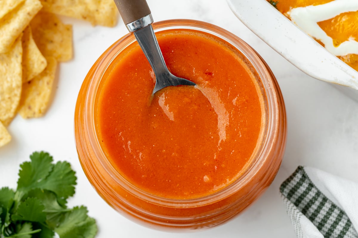 overhead shot of spoon in jar of homemade enchilada sauce