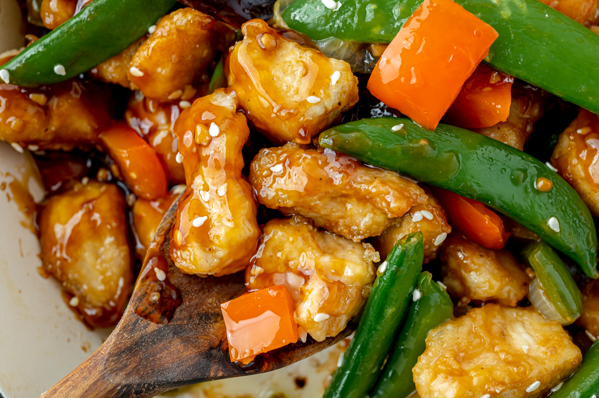 close up shot of szechuan chicken on wooden spoon in pan