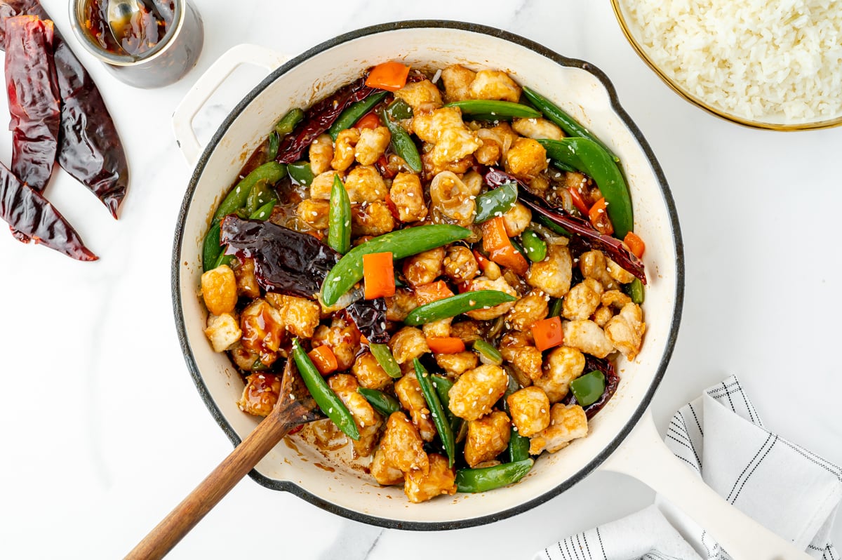 overhead shot of wooden spoon in pan of szechuan chicken