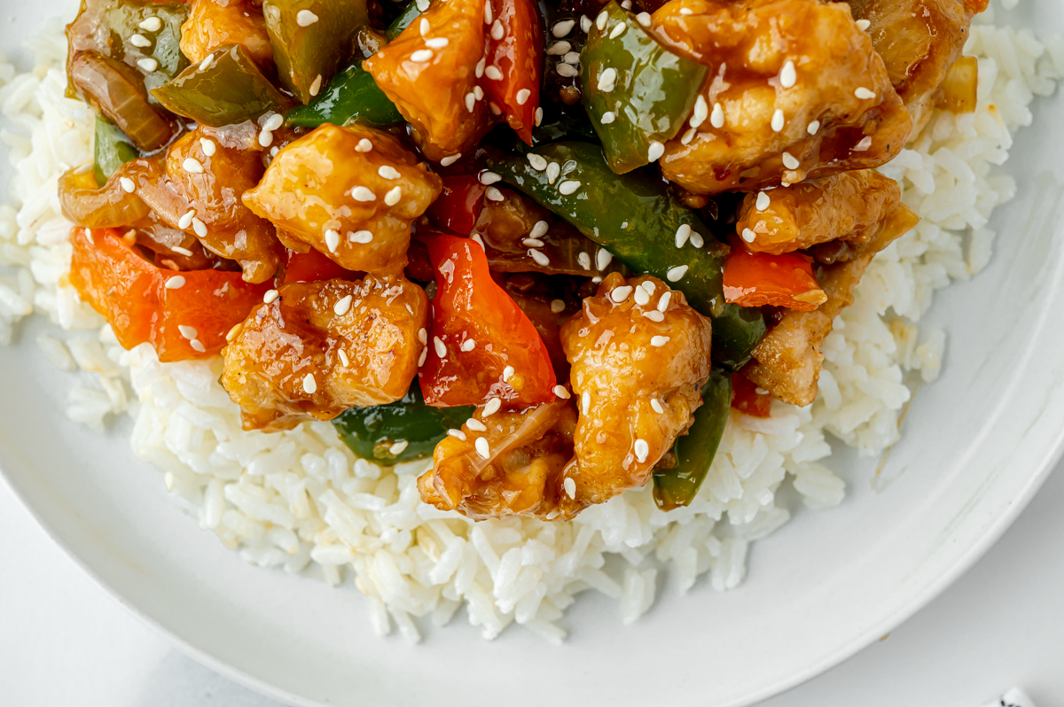 close up overhead shot of szechuan chicken over rice on a plate