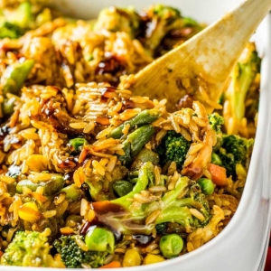 angled shot of wooden spoon in teriyaki chicken casserole