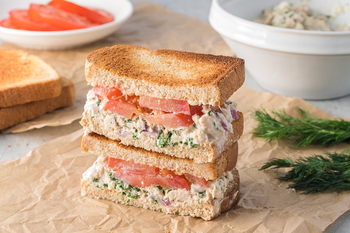 angled shot of stack of tuna salad sandwich halves on parchment paper