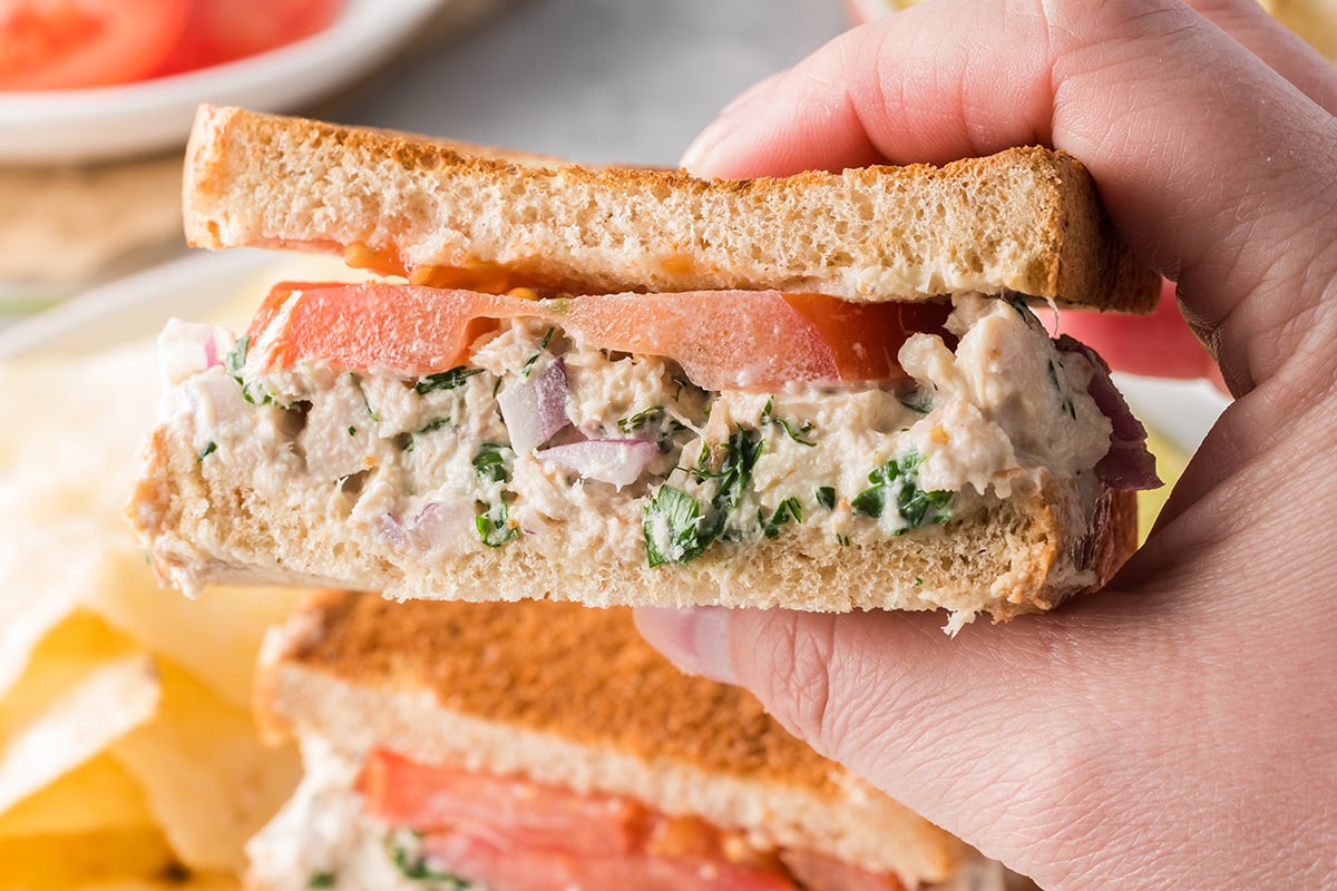 hand holding half a tuna salad sandwich