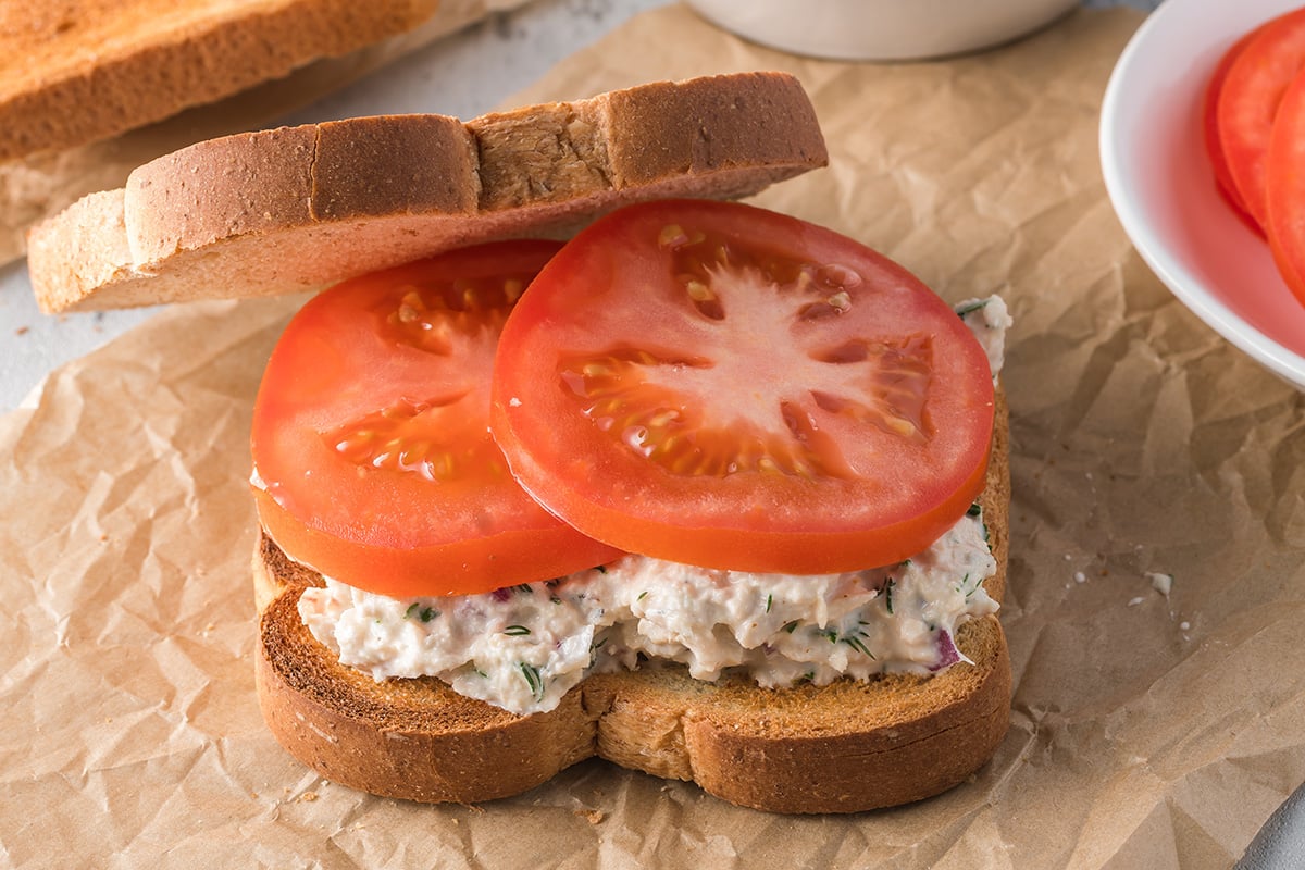 angled shot of tomato slices on tuna salad sandwich