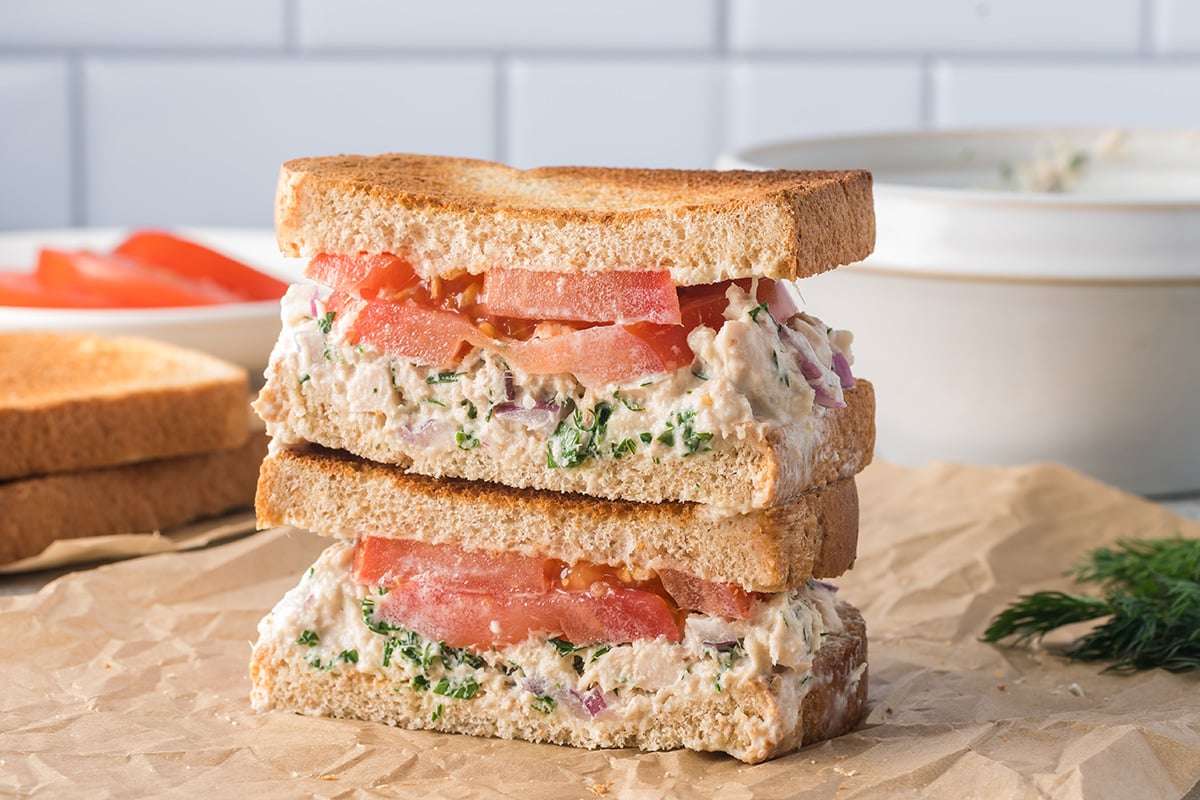 straight on shot of stack of tuna salad sandwich halves on parchment paper