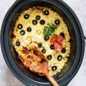 overhead shot of wooden spoon in slow cooker of chicken enchiladas