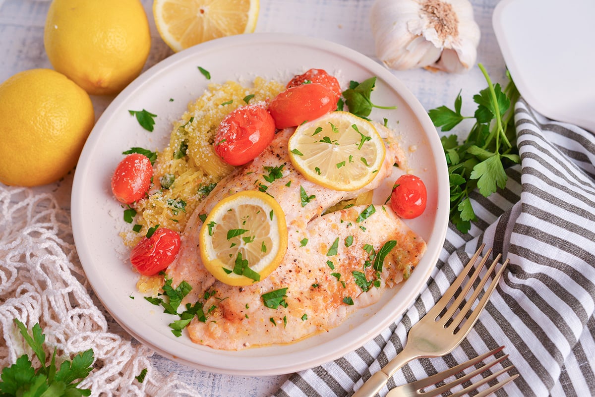 angled shot of lemon garlic butter baked tilapia on plate