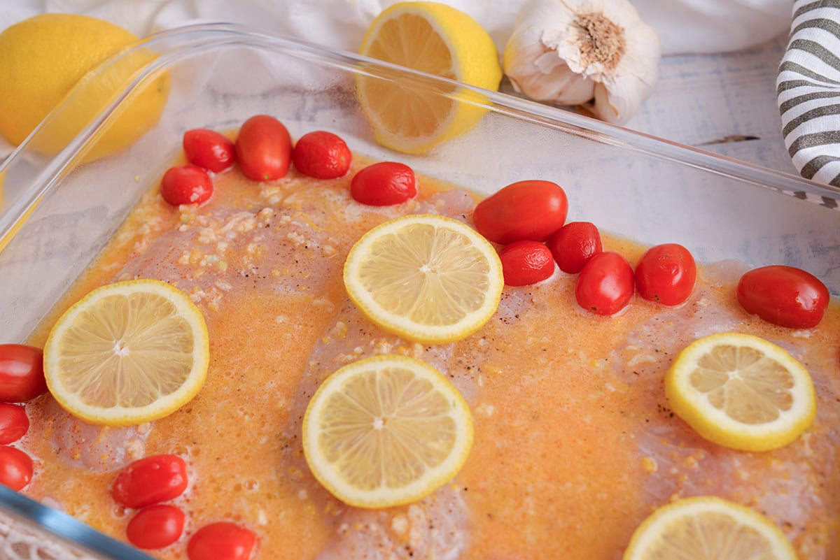 angled shot of lemon slices on tilapia in baking dish