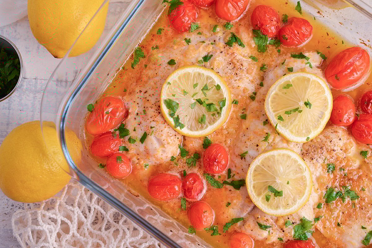 close up overhead shot of lemon garlic butter baked tilapia in baking dish