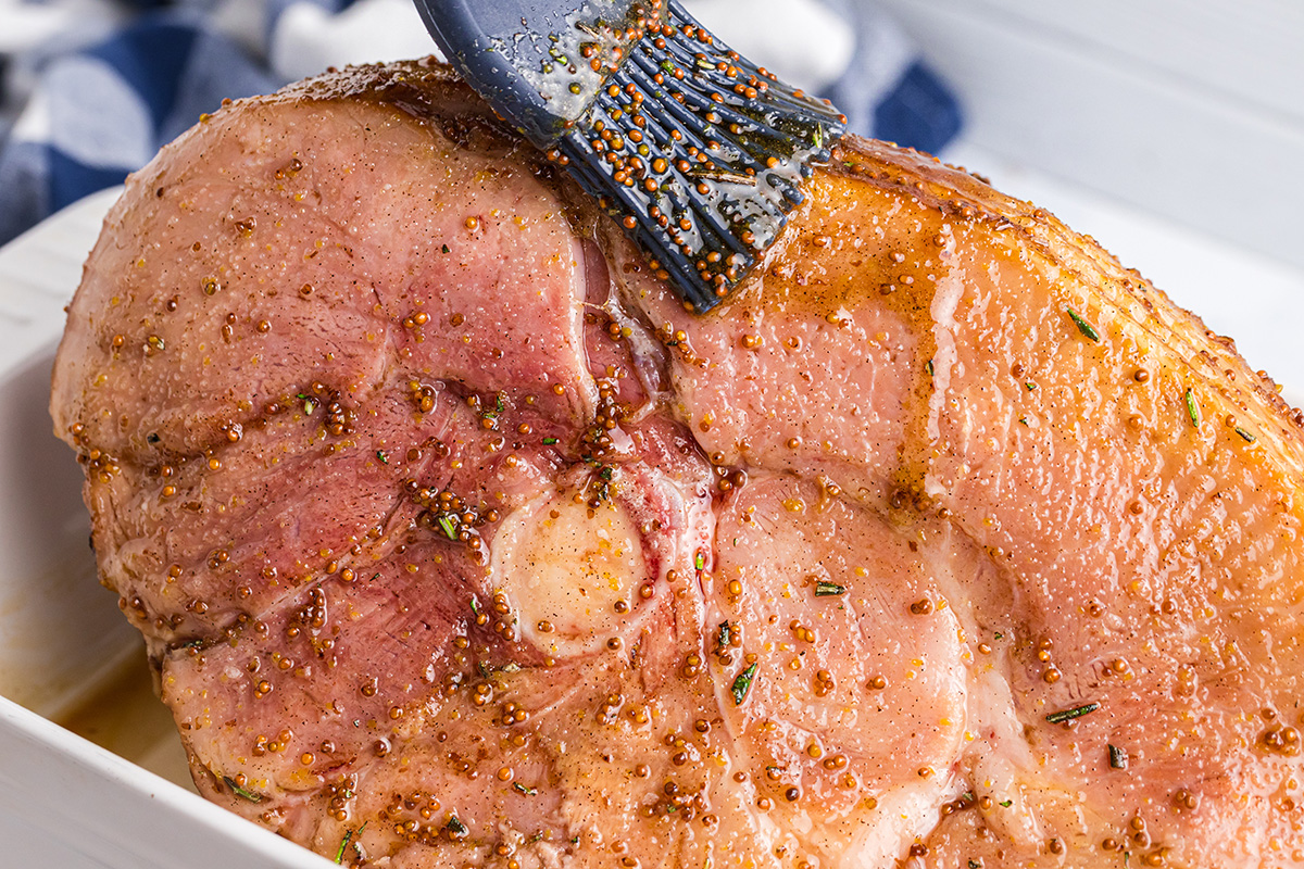 straight on shot of basting ham with brown sugar mustard glaze