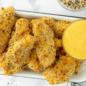 overhead shot of tray of everything seasoning chicken tenders with honey mustard