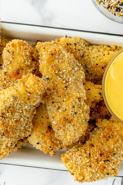 overhead shot of tray of everything seasoning chicken tenders with honey mustard