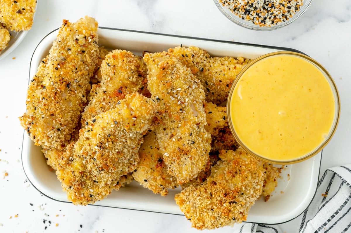 overhead shot of tray of everything seasoning chicken tenders with honey mustard