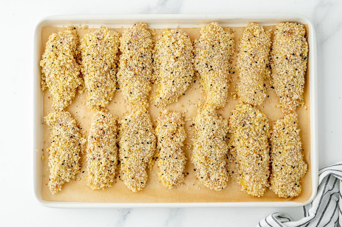 coated chicken tenders on baking sheet