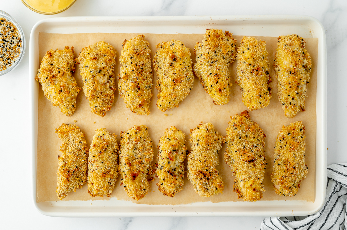 overhead shot of everything seasoning chicken tenders on sheet pan