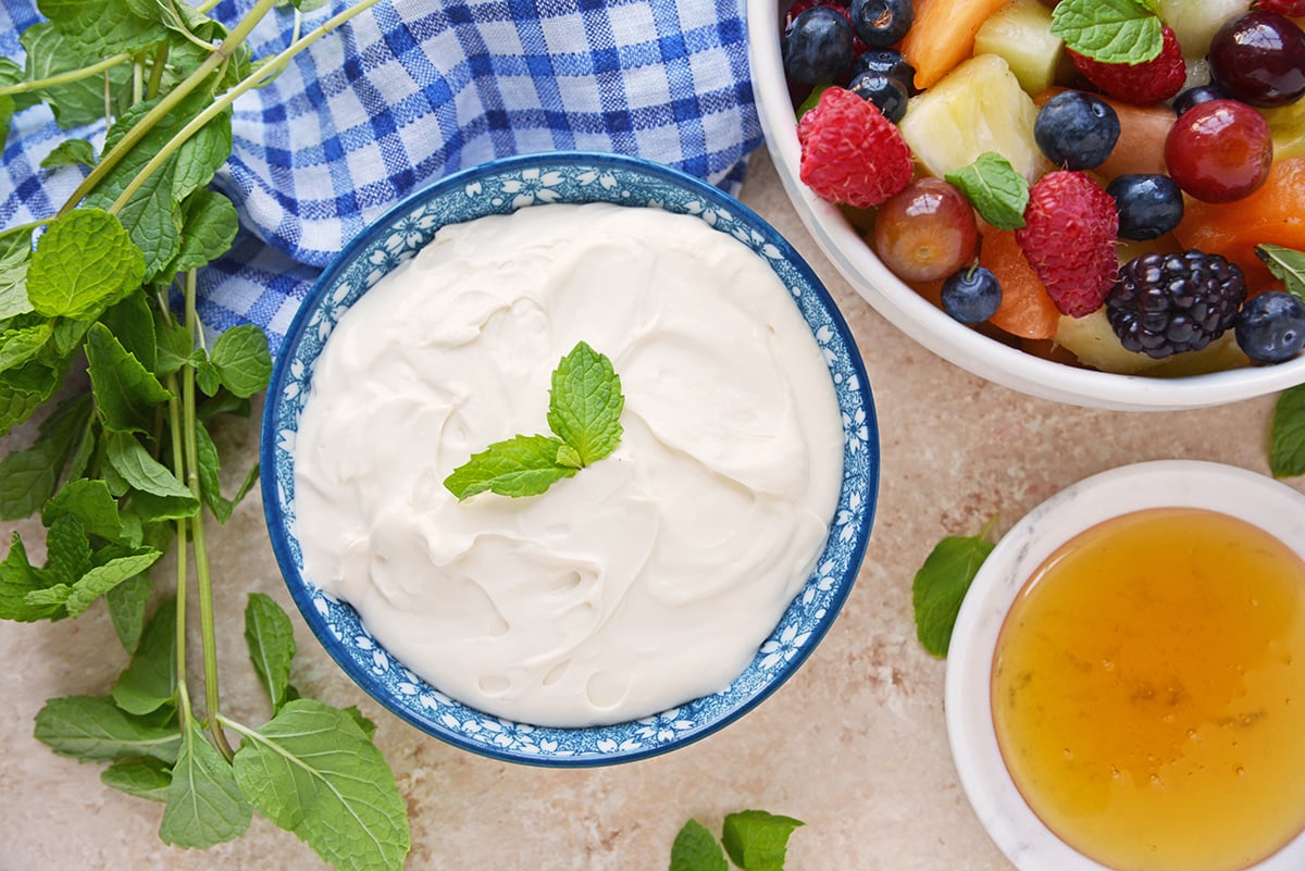 overhead blue bowl of cream cheese fruit dip with fresh fruit and blue linen 