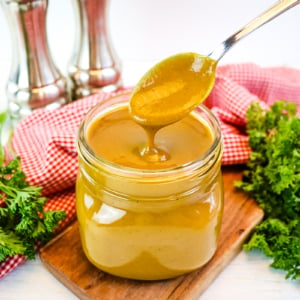 angled shot of spoon in jar of golden bbq sauce