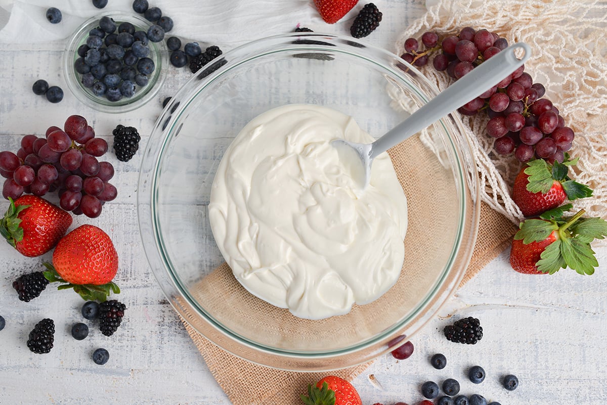 creamy fruit dip being mixed in a glass mixing bowl