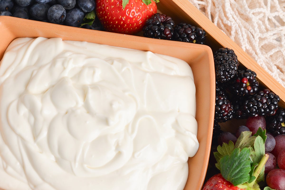close up of cream cheese fruit dip in a brown serving bowl with fresh fruit