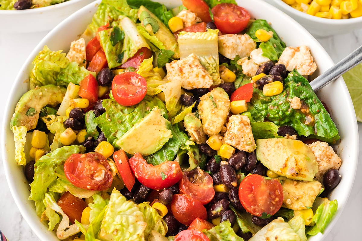 close up angled shot of tossed mexican salad with fork in bowl