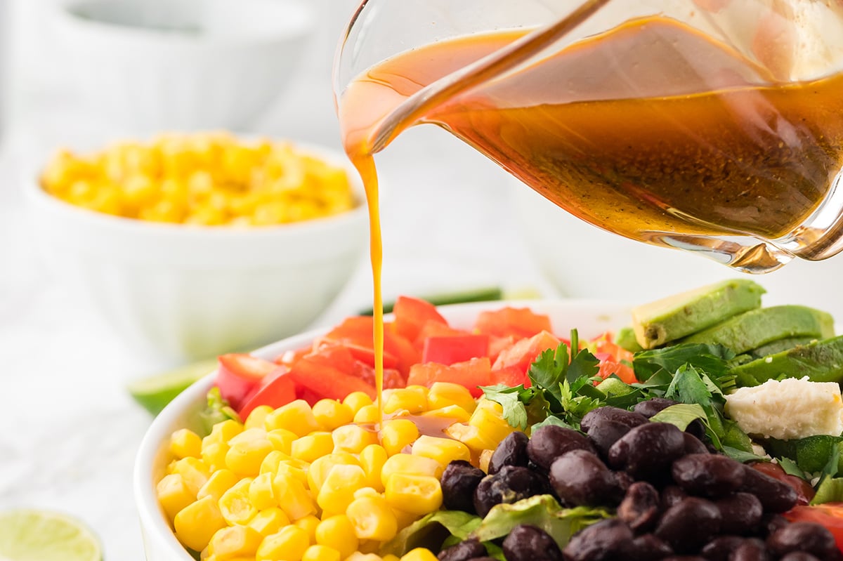 dressing pouring onto mexican salad