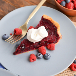 angled shot of slice of pie on plate topped with whipped cream