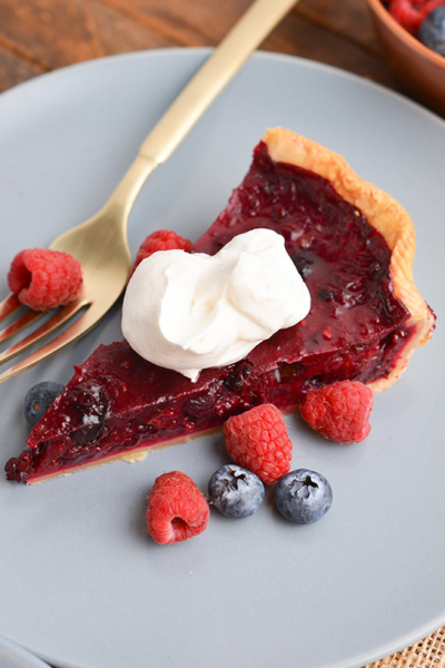 angled shot of slice of pie on plate topped with whipped cream