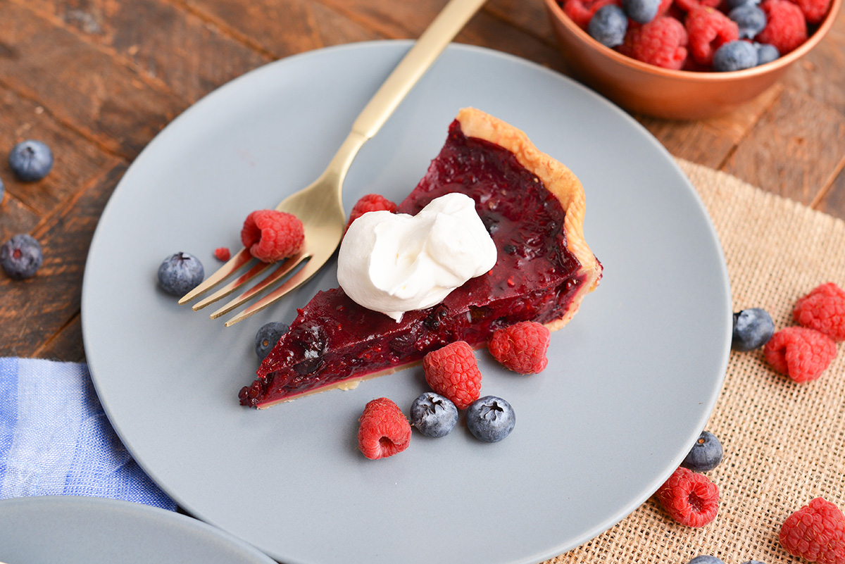 angled shot of slice of pie on plate topped with whipped cream