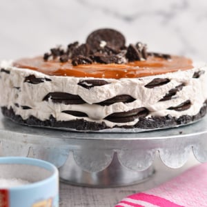 layered oreo icebox cake with caramel topping on a metal cake stand