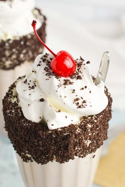 close up of oreo milkshake with whipped cream and a cherry