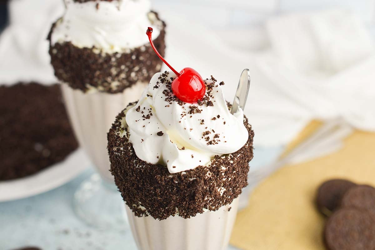 close up of oreo milkshake with whipped cream and a cherry