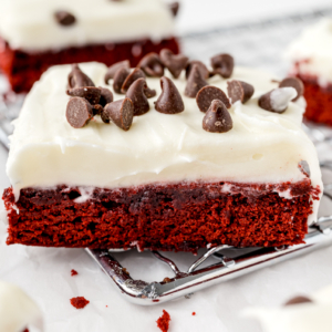 angle view of red velvet brownie with thick cream cheese frosting and chocolate chips