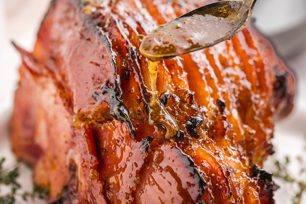 close up of spoon adding glaze to ham