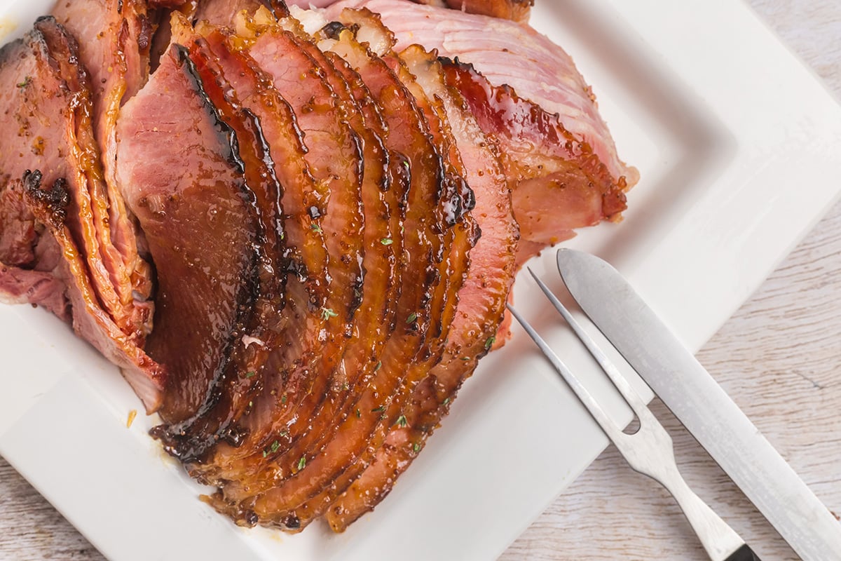 close up overhead shot of sliced rielsing peach glazed ham on platter